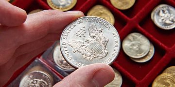 American dollar in hand of numismatist and magnifying glass