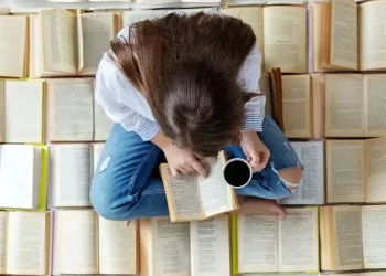 ragazza legge libro su un letto di libri