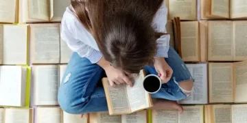 ragazza legge libro su un letto di libri